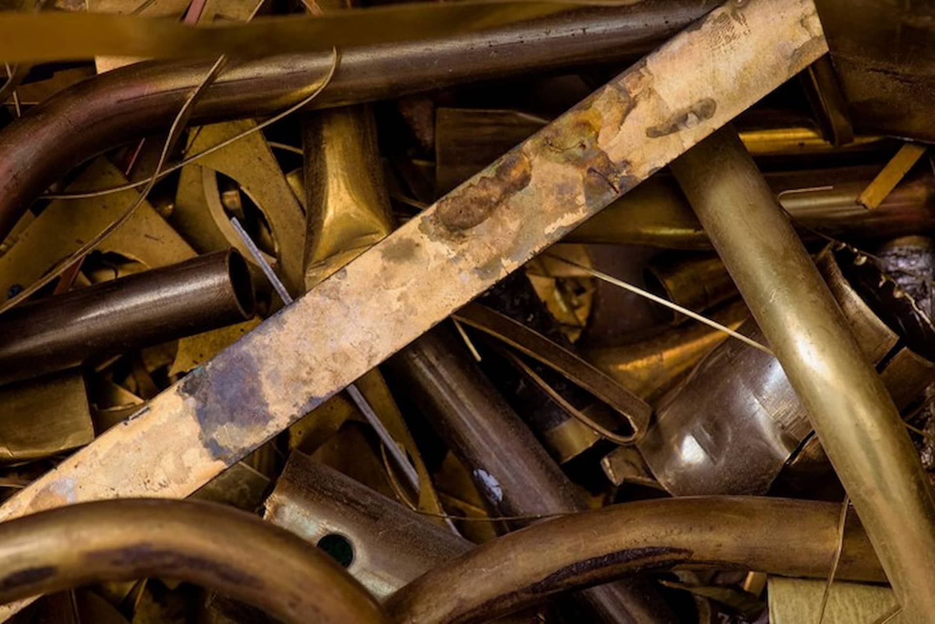 A pile of old yellow scrap brass metal pipes and miscellaneous items