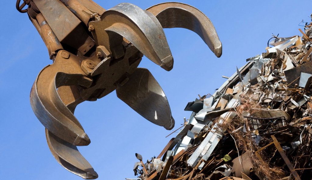 Extractor working a steel pile to recycle at metal yard